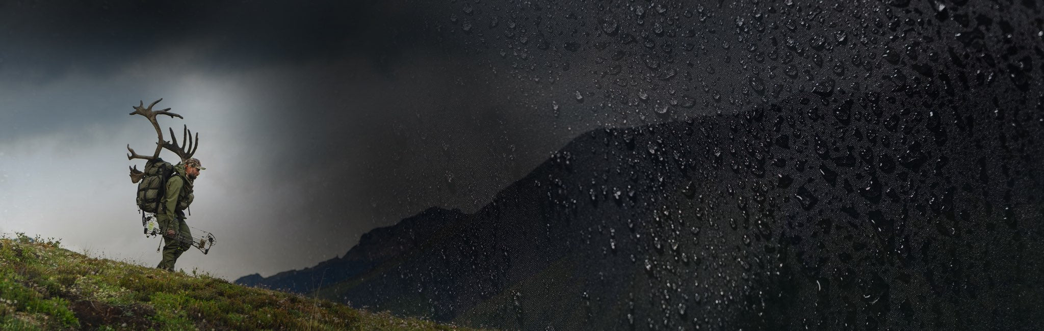 A dramatic outdoor scene showing a person carrying a large caribou skull on their shoulder while hiking up a grassy slope, with dark storm clouds and a mountain in the background.