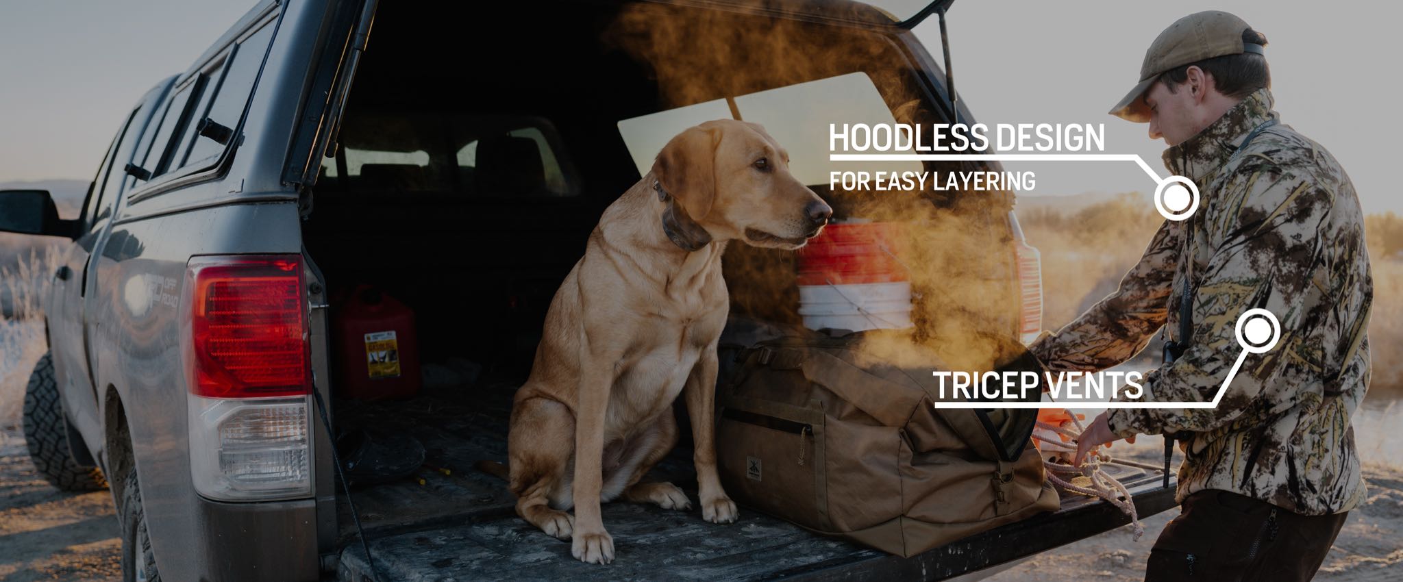 Camo hoodless jacket with tricep vents on man next to truck.
