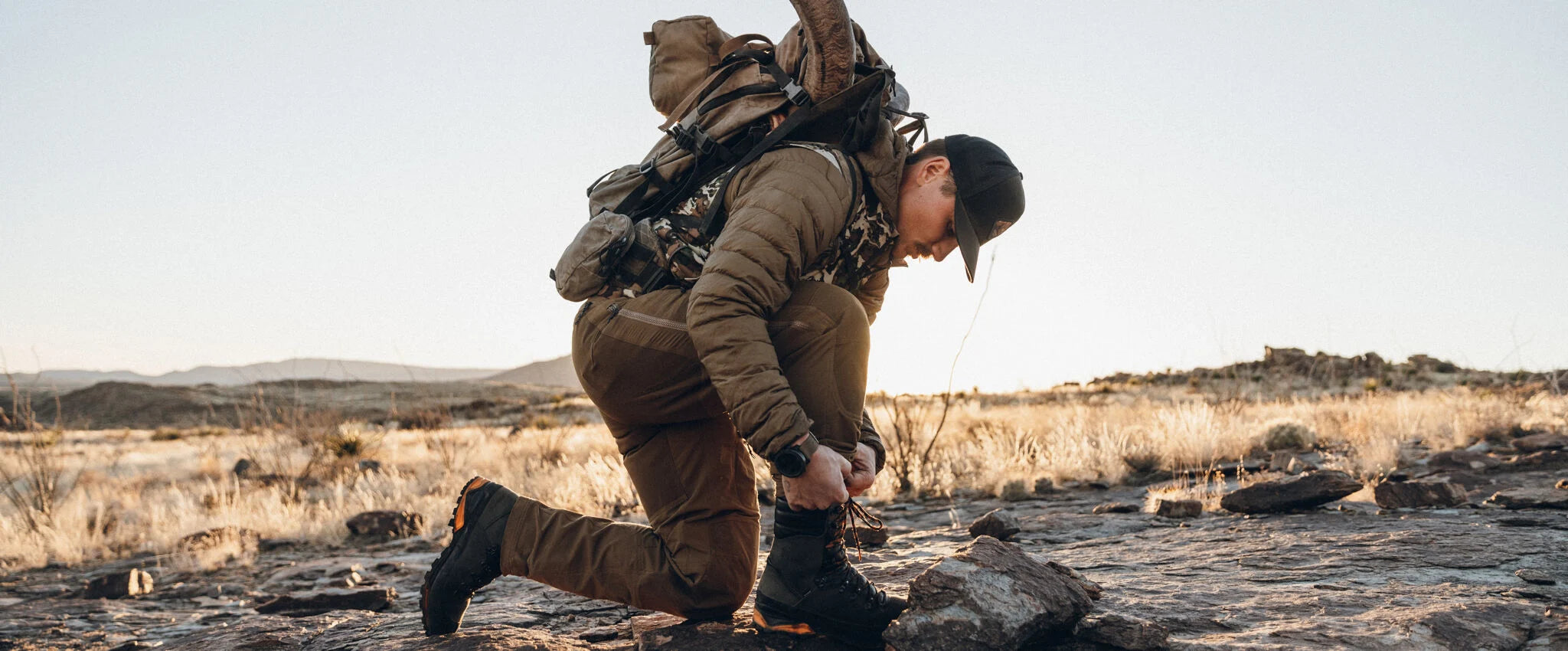 Black hiking boot with orange sole and rugged tread being laced.