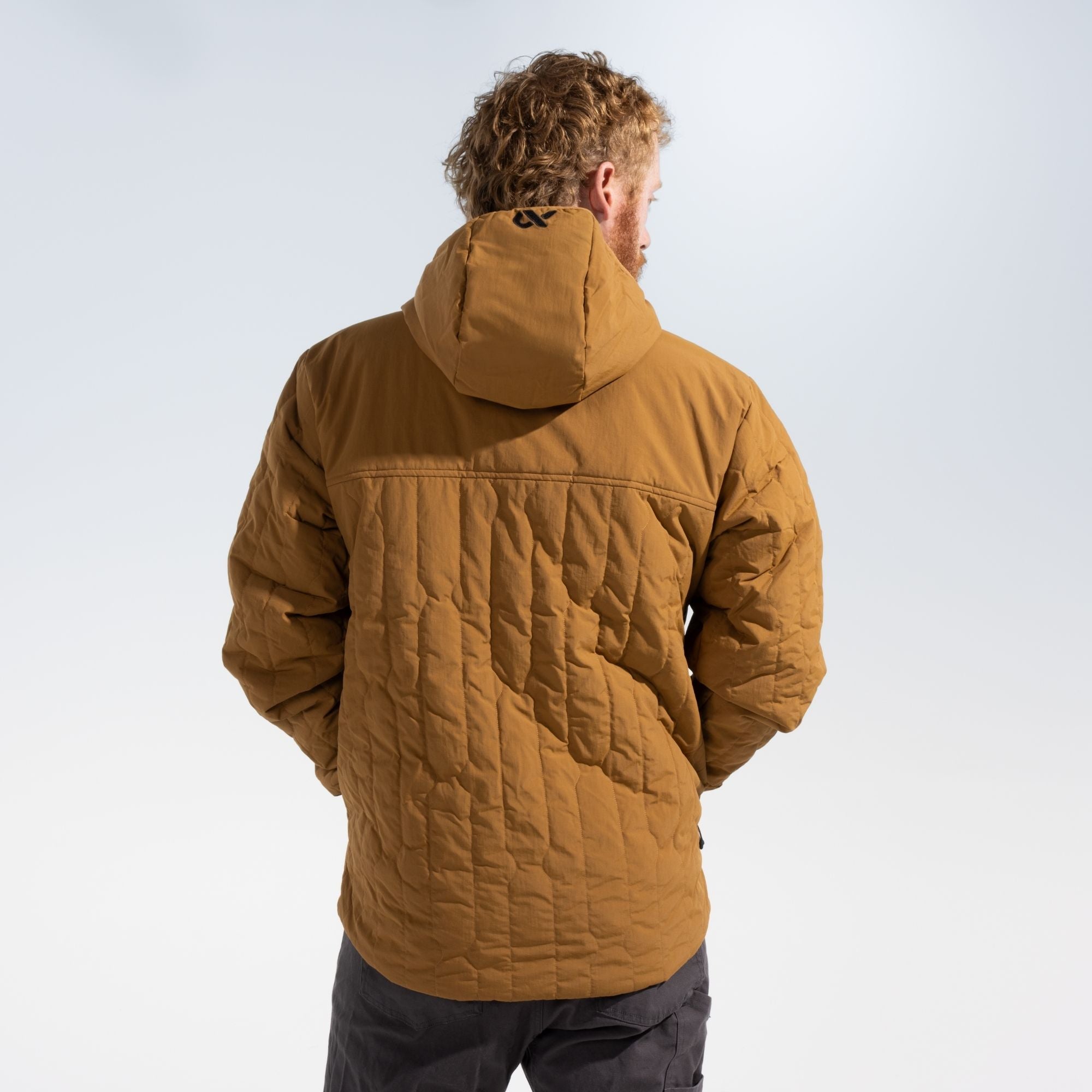 Man shown from behind wearing a rust outpost jacket with black FIRST LITE branding on the jacket hood.