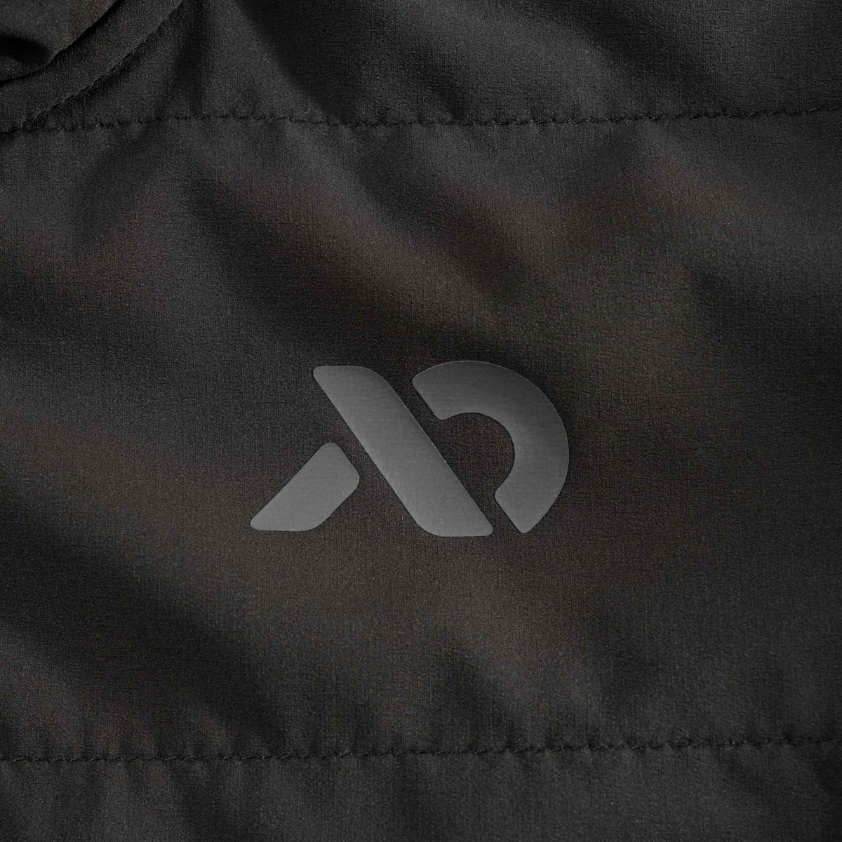 Close up to the grey FIRST LITE logo on the black puffer jacket.