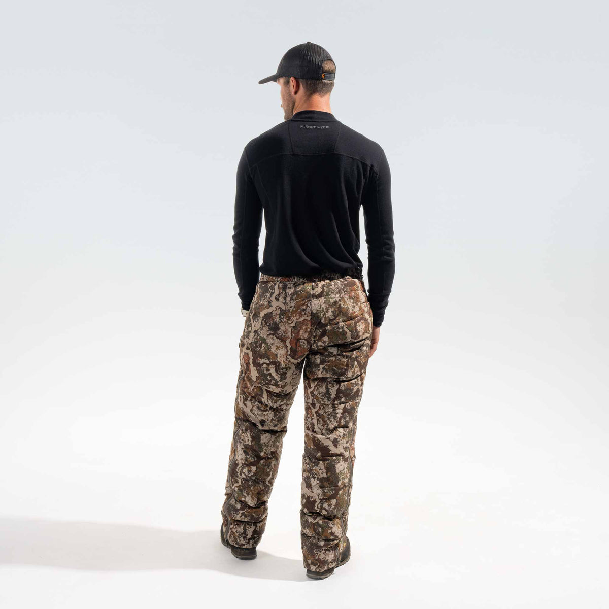 Behind shot of a man wearing black cap and shirt and camo pants.