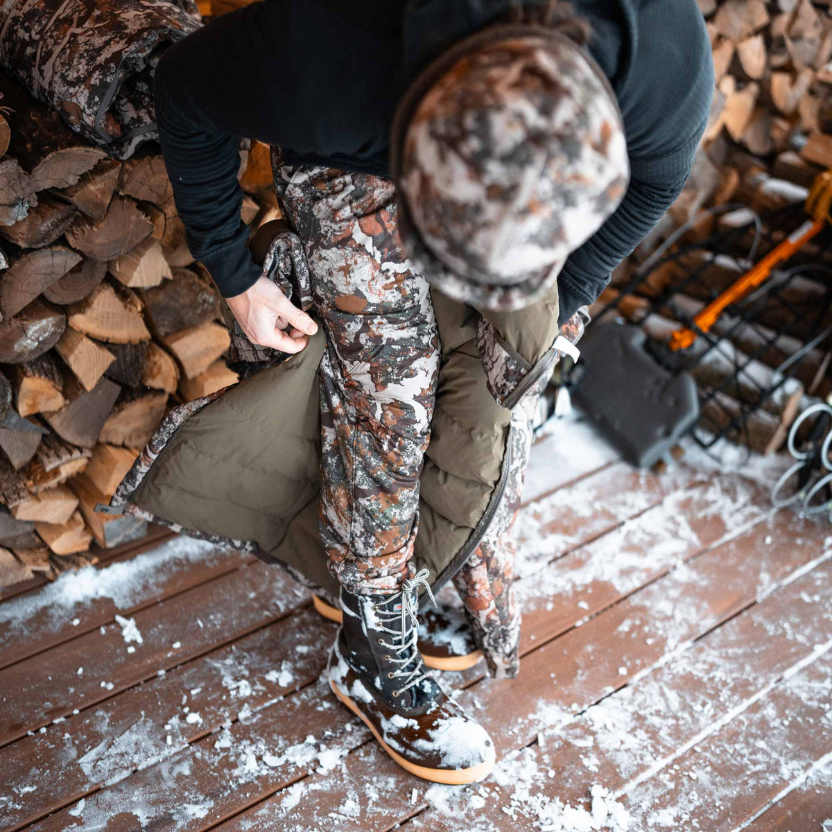 Man inclined showing his camo pants and brown boots covered in snow.