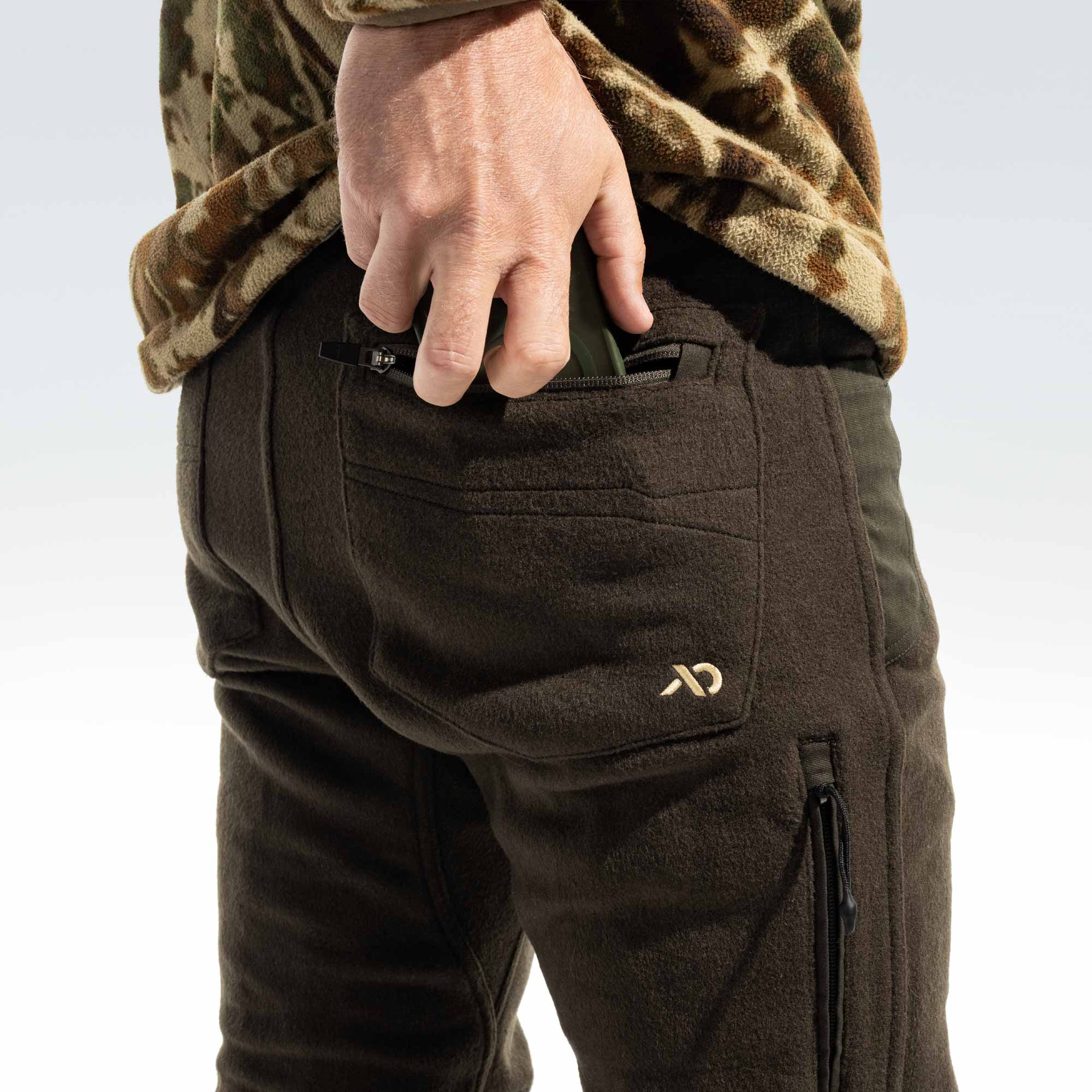 Man putting a phone inside the back pocket of his pants, the pocket has FIRST LITE logo.