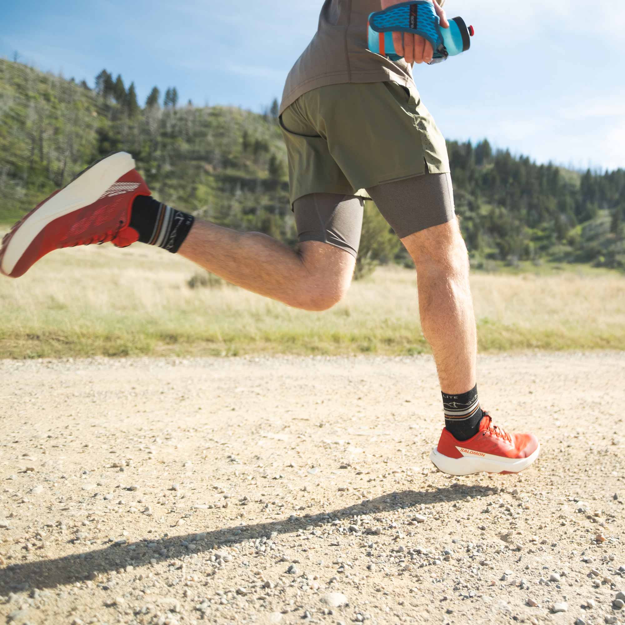Person running on a trail with greenery in the background