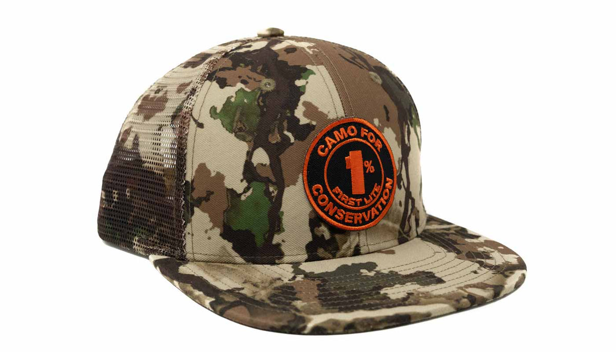 A camouflage trucker cap with a circular orange and black 'Camouflage for Conservation 1% Pesticide' patch on the front, set against a plain white background.
