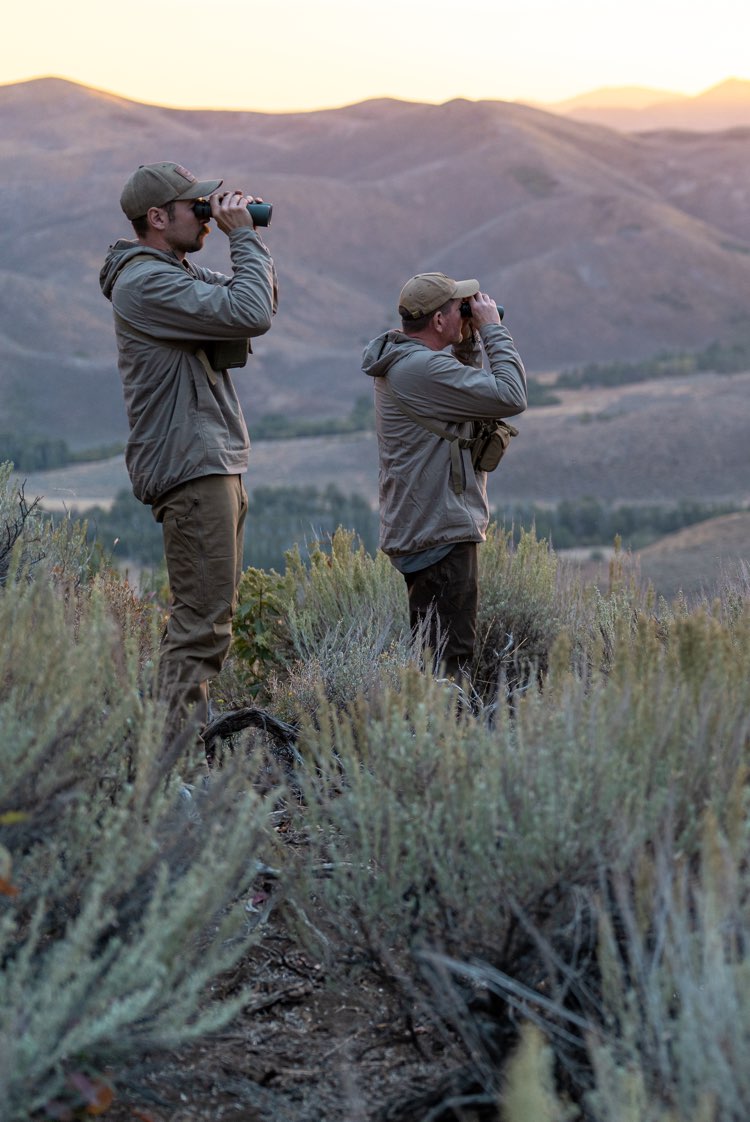 father and son using binoculars in a desert landscape.