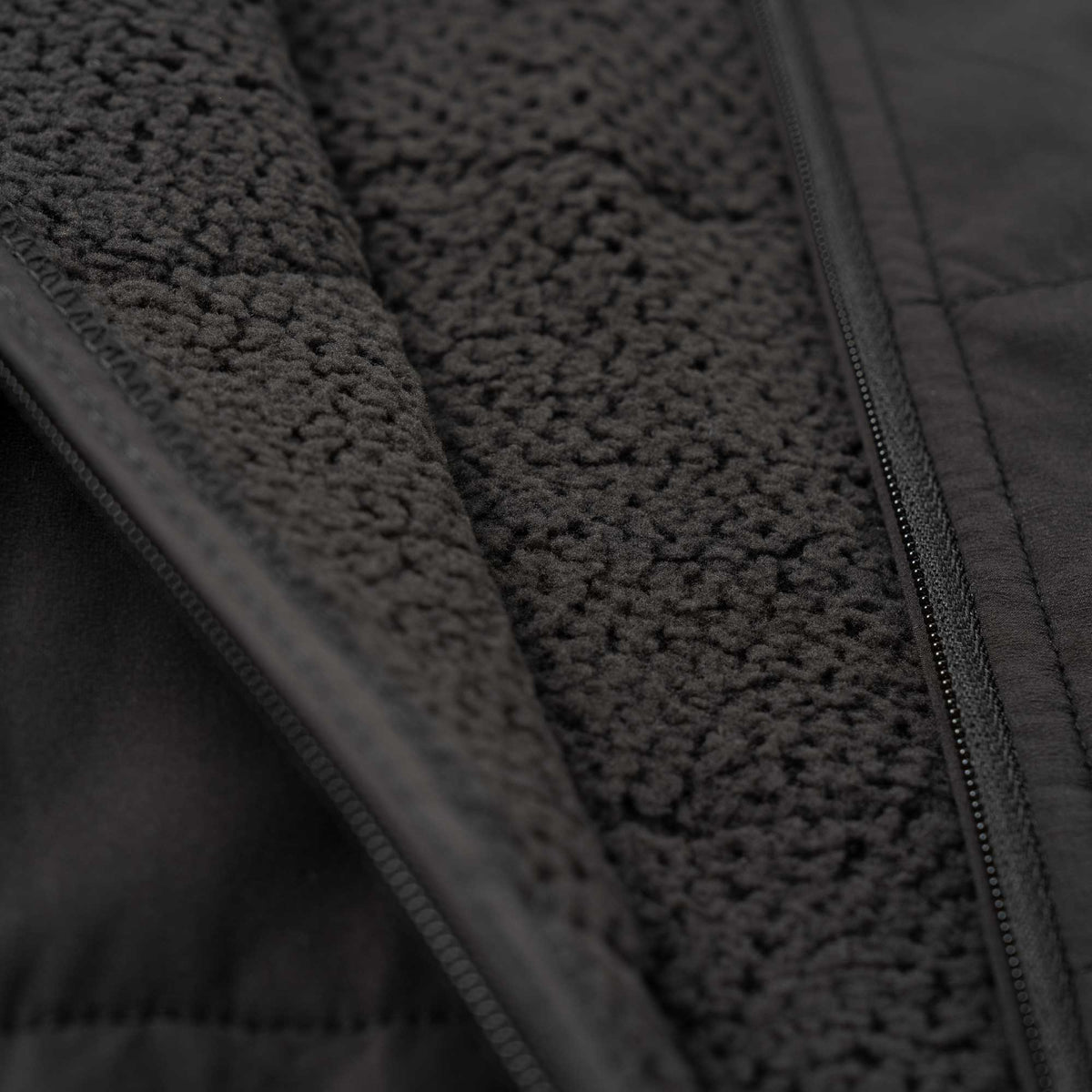 Close up to the zip and interior materials of the black puffer jacket.