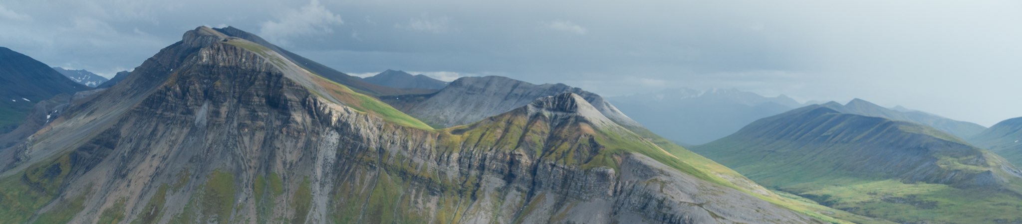 Panoramic view of a mountain landscape with rugged peaks and valleys.