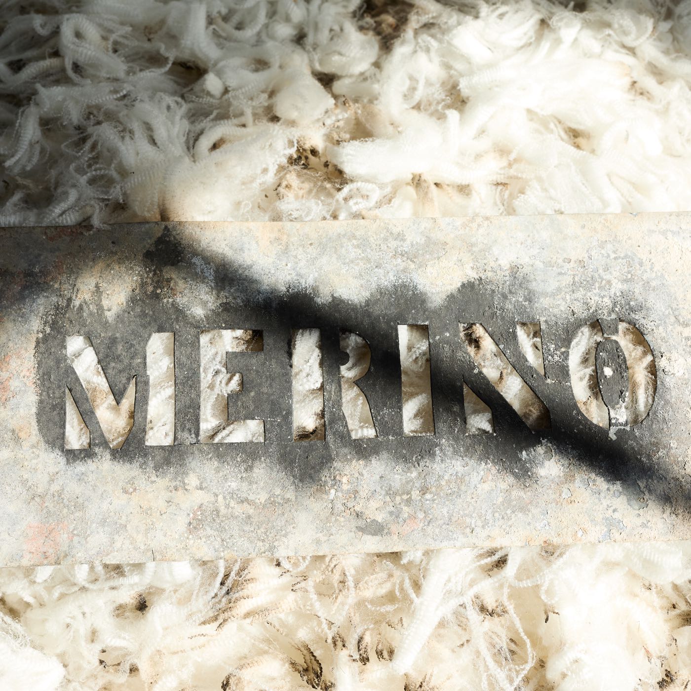 Cream raw Merino wool with 'MERINO' spelled out by a rustic stencil.